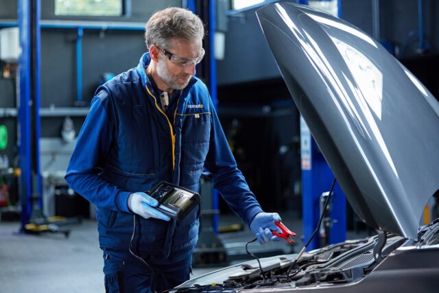 Homme atelier Norauto en train de réaliser un diagnostic sur une batterie de voiture