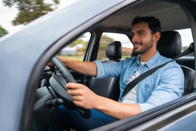 Homme heureux et serein conduisant sa voiture et souriant






