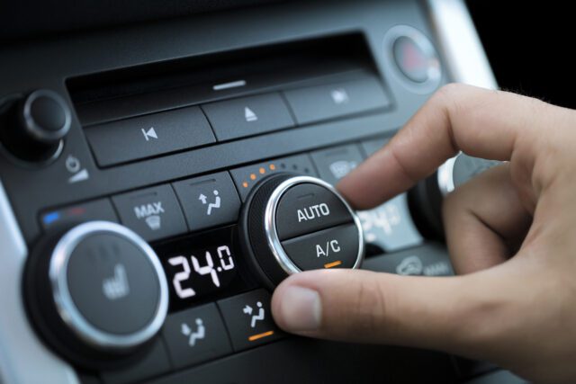 Main d'un homme activant le système de climatisation d'une voiture.