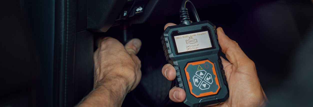 Mécanicien automobile utilisant un scanner OBD, outil de lecture de codes, pour vérifier les erreurs moteur et effectuer un diagnostic.