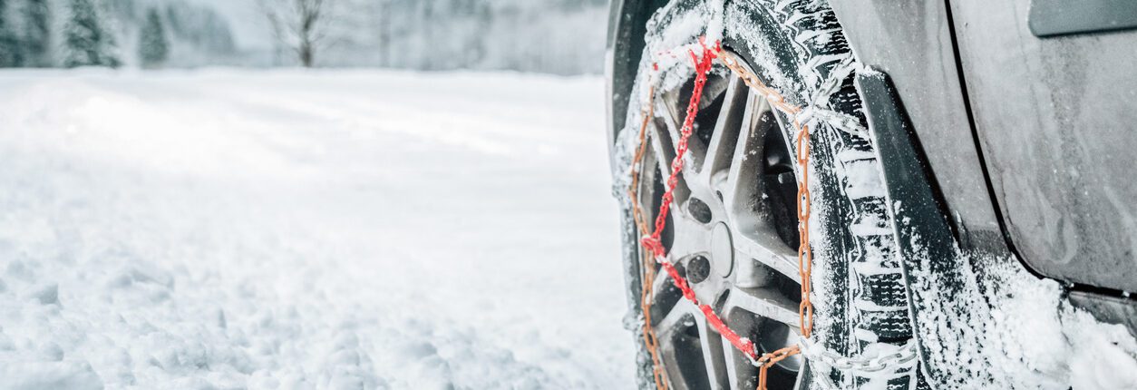 Chaînes neige sur le pneu d'une voiture. Détail de la roue sur une route hivernale, les chaînes neige pour une roue de voiture sur une route dans un pays enneigé.