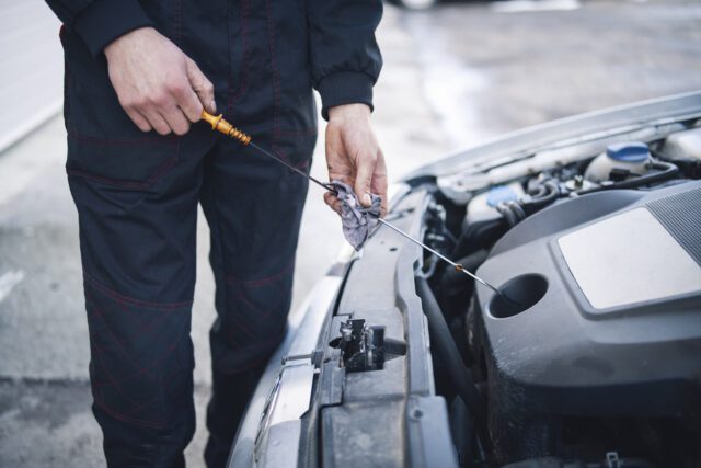 Mécanicien effectuant l'entretien de la voiture, vérification et remplacement de l'huile moteur.